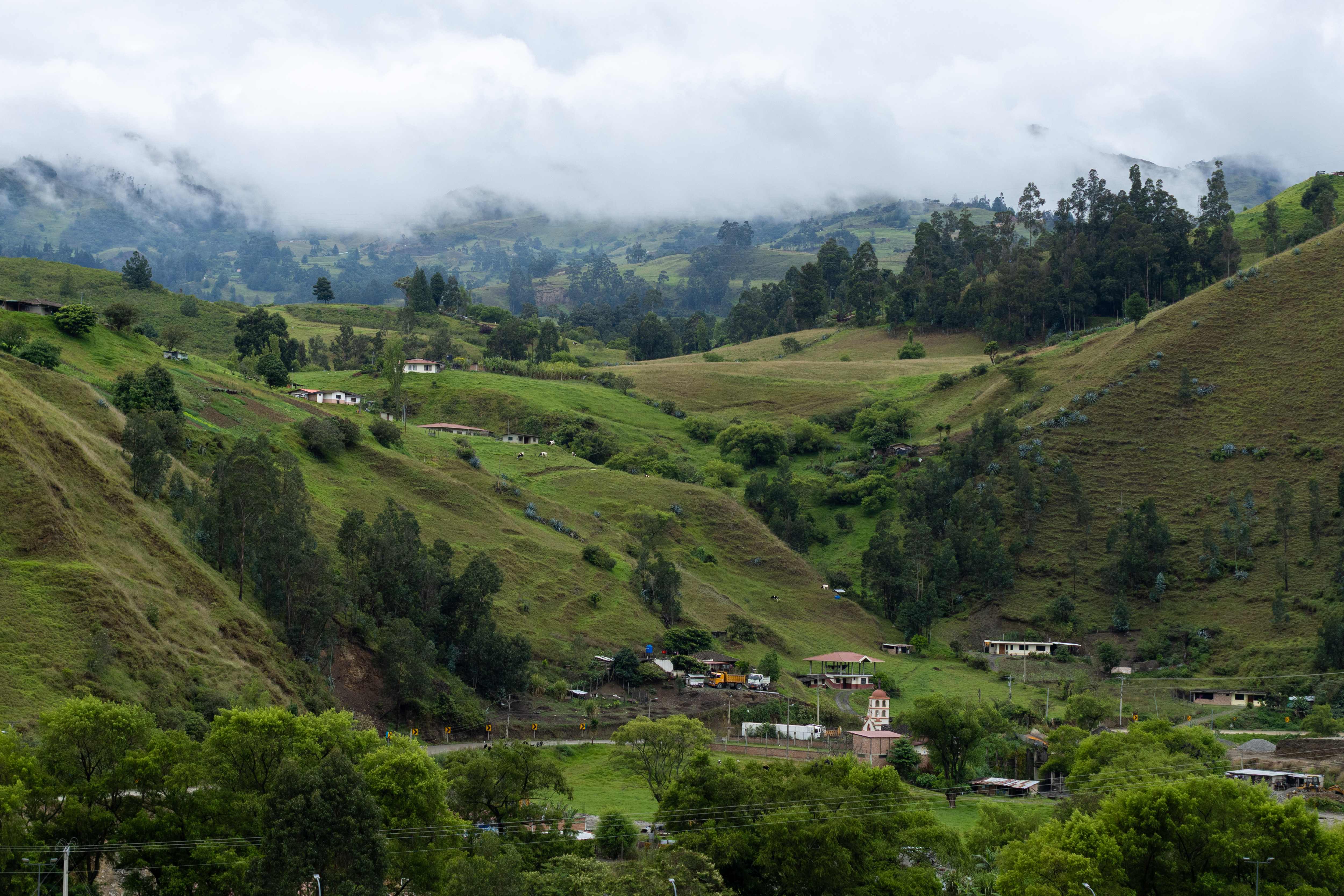 Green, fog-draped hills and a small village in a mountain valley
